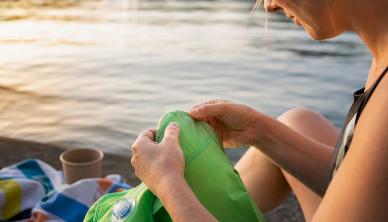 Ein Elternteil überprüft am Beckenrand die Schwimmhilfe seines Kindes.