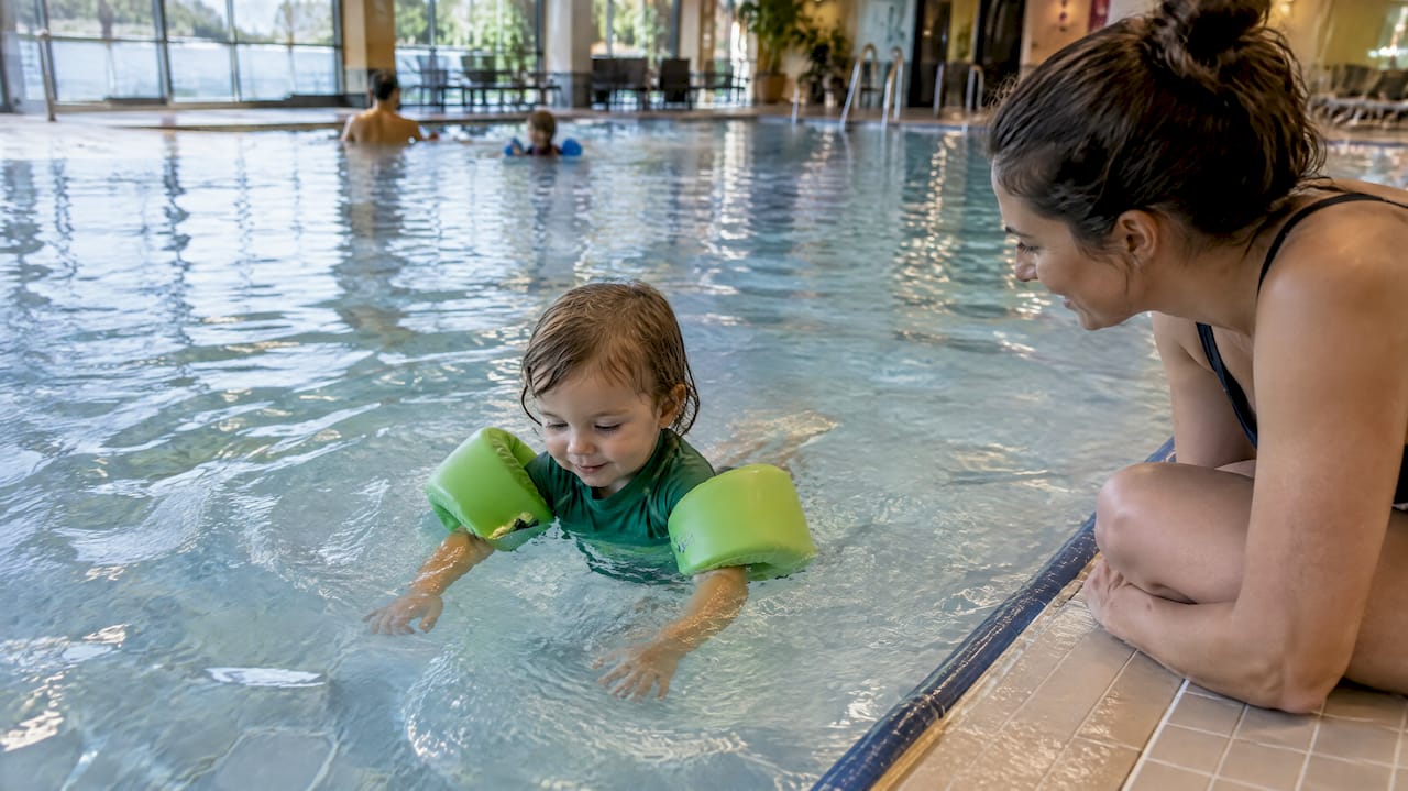 Kind trainiert unter Aufsicht mit stabilen Schwimmflügeln