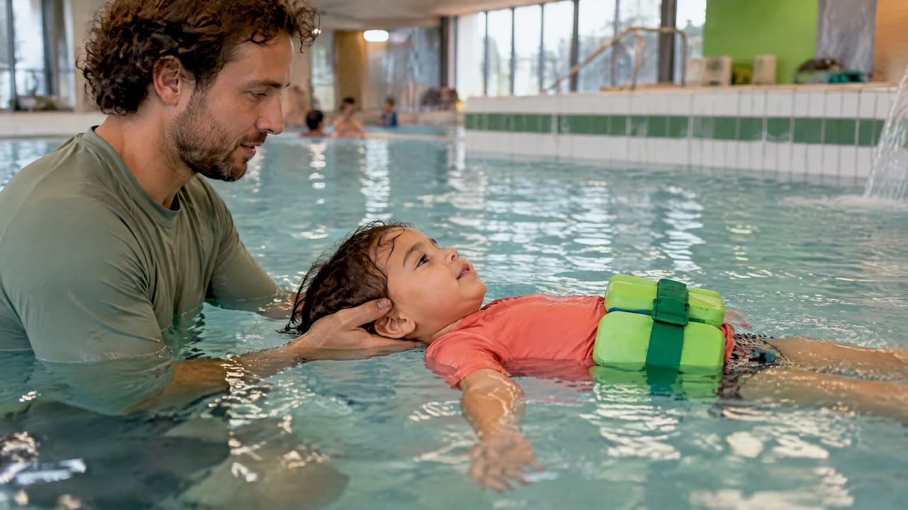 Kind trainiert mit Schwimmgürtel das Schwimmen auf dem Rücken
